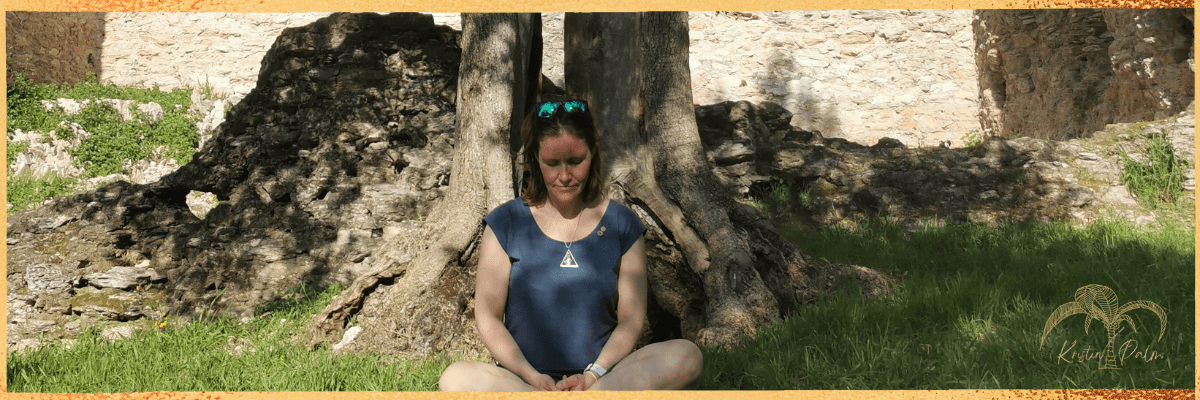 Hier siehst du Kristin Palm im Schneidersitz auf einer Wiese sitzen. Sie meditiert. Meditation ist wichtig zur Unterstützung der Heilung nach einem Kaiserschnitt.